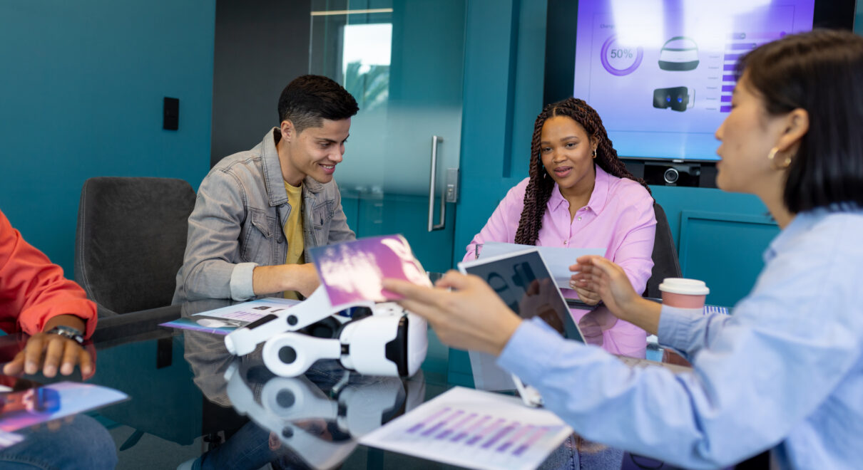 Colleagues from diverse backgrounds discuss VR tech in a modern business office.