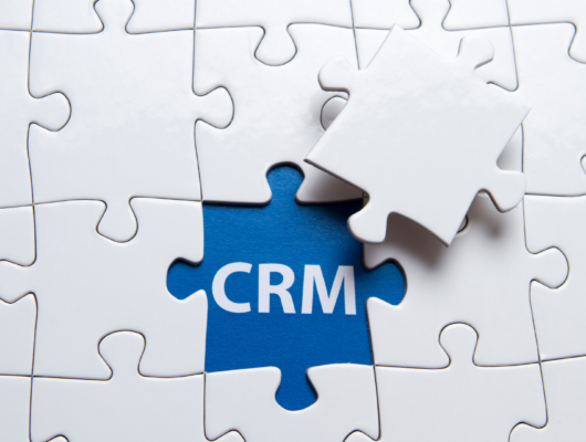 Une pièce de puzzle marquée CRM complétant un ensemble, illustrant un CRM pour agence immobilière.